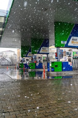 Bir OMV benzin istasyonunun dışı. Benzin pompaları ve arabalar kar yağarken yakıt ikmali yapıyorlar.