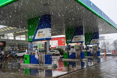 Bir OMV benzin istasyonunun dışı. Benzin pompaları ve arabalar kar yağarken yakıt ikmali yapıyorlar.