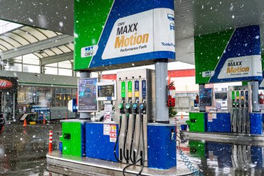 Bir OMV benzin istasyonunun dışı. Benzin pompaları ve arabalar kar yağarken yakıt ikmali yapıyorlar.
