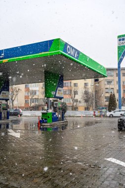 Bir OMV benzin istasyonunun dışı. Benzin pompaları ve arabalar kar yağarken yakıt ikmali yapıyorlar.