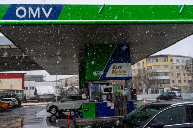 Bir OMV benzin istasyonunun dışı. Benzin pompaları ve arabalar kar yağarken yakıt ikmali yapıyorlar.