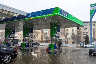 Bir OMV benzin istasyonunun dışı. Benzin pompaları ve arabalar kar yağarken yakıt ikmali yapıyorlar.