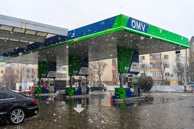 Bir OMV benzin istasyonunun dışı. Benzin pompaları ve arabalar kar yağarken yakıt ikmali yapıyorlar.
