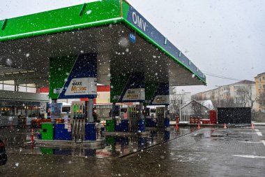 Bir OMV benzin istasyonunun dışı. Benzin pompaları ve arabalar kar yağarken yakıt ikmali yapıyorlar.