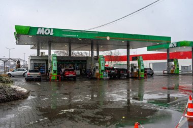 Bir MOL benzin istasyonunun dışı. Benzin pompaları ve arabalar kar yağarken yakıt ikmali yapıyorlar.