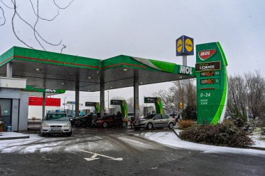 Bir MOL benzin istasyonunun dışı. Benzin pompaları ve arabalar kar yağarken yakıt ikmali yapıyorlar.