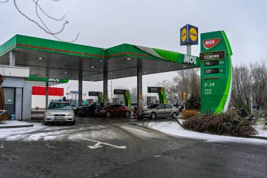 Bir MOL benzin istasyonunun dışı. Benzin pompaları ve arabalar kar yağarken yakıt ikmali yapıyorlar.