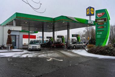 Bir MOL benzin istasyonunun dışı. Benzin pompaları ve arabalar kar yağarken yakıt ikmali yapıyorlar.