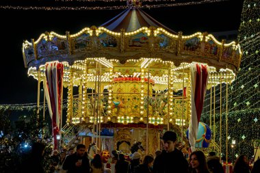 Gece Bükreş Noel pazarında süslü ağaçlar, renkli dönme dolaplar ve tatil pazarının tadını çıkaran insanlar