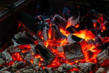 Aktif olarak yanan ateş közleri. Yanan kömürlerin arka planı. Geceleri yanan kömürlerin titreşimi