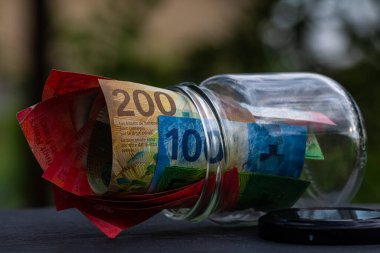 İsviçre frangı CHF banknotu cam kavanozda para biriktiriyor. Tüketim ve ekonomi. İş, bahşiş, finans, tasarruf, bankacılık ve insan kavramı