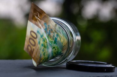 İsviçre frangı CHF banknotu cam kavanozda para biriktiriyor. Tüketim ve ekonomi. İş, bahşiş, finans, tasarruf, bankacılık ve insan kavramı