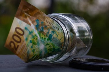 İsviçre frangı CHF banknotu cam kavanozda para biriktiriyor. Tüketim ve ekonomi. İş, bahşiş, finans, tasarruf, bankacılık ve insan kavramı