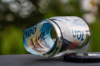 İsviçre frangı CHF banknotu cam kavanozda para biriktiriyor. Tüketim ve ekonomi. İş, bahşiş, finans, tasarruf, bankacılık ve insan kavramı
