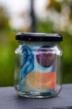 İsviçre frangı CHF banknotu cam kavanozda para biriktiriyor. Tüketim ve ekonomi. İş, bahşiş, finans, tasarruf, bankacılık ve insan kavramı