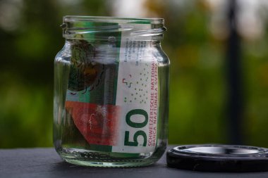 İsviçre frangı CHF banknotu cam kavanozda para biriktiriyor. Tüketim ve ekonomi. İş, bahşiş, finans, tasarruf, bankacılık ve insan kavramı