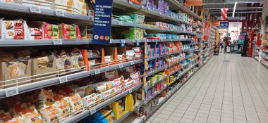 Süpermarket koridoru rafları dolduran ürünlerle dolu. Carrefour süpermarketi, Avrupa 'nın en büyük süpermarket zincirlerinden biri.