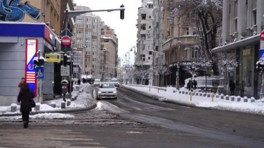 Bükreş 'te kar fırtınası ve yoğun kar yağışı var. Trafikte arabalar ve insanlar karlı yollarda yürüyor.