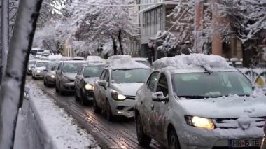 Bükreş 'te kar fırtınası ve yoğun kar yağışı var. Trafikte arabalar ve insanlar karlı yollarda yürüyor.