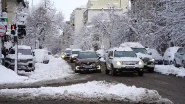 Bükreş 'te kar fırtınası ve yoğun kar yağışı var. Trafikte arabalar ve insanlar karlı yollarda yürüyor.