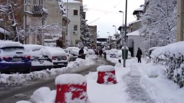 Bükreş 'te kar fırtınası ve yoğun kar yağışı var. Trafikte arabalar ve insanlar karlı yollarda yürüyor.