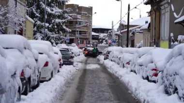 Bükreş 'te kar fırtınası ve yoğun kar yağışı var. Trafikte arabalar ve insanlar karlı yollarda yürüyor.