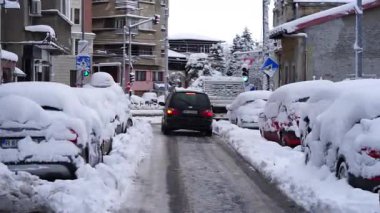 Bükreş 'te kar fırtınası ve yoğun kar yağışı var. Trafikte arabalar ve insanlar karlı yollarda yürüyor.