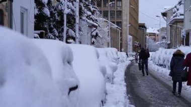 Bükreş 'te kar fırtınası ve yoğun kar yağışı var. Trafikte arabalar ve insanlar karlı yollarda yürüyor.