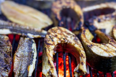 Sıcak ızgarada pişen taze balık filetoları. Sağlıklı açık hava pikniği için duman ve ateş alevleri.