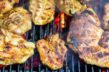 Domuz bifteği ve sosis sıcak ızgarada pişiyor. Açık hava pikniği için duman ve alevlerle.