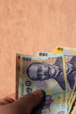 Romen para banknotlarını tutan, kağıt doku ve Rumen LEI para biriminin sembollerini gösteren bir adam.