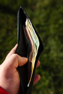 Romen LEI banknotlarıyla el ele tutuşan adamın elinde kağıt doku ve Rumen LEI para birimi sembolleri görülüyor