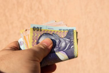 Romen para banknotlarını tutan, kağıt doku ve Rumen LEI para biriminin sembollerini gösteren bir adam.