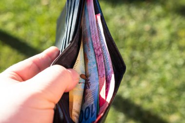 Elinde İsviçre frangı banknotlarıyla el ele tutuşan bir adam, İsviçre CHF para biriminin kağıt dokusu ve sembollerini gösteriyor.