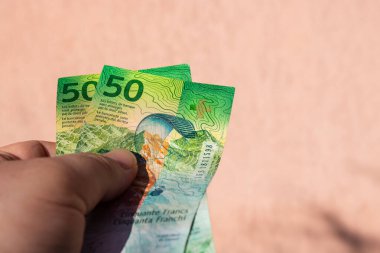 İsviçre frangı para banknotlarını tutan adam, İsviçre CHF para biriminin kağıt dokusu ve sembollerini gösteriyor