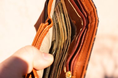 Amerikan dolarının kağıt dokusu ve sembollerini gösteren ABD Doları banknotlarıyla el ele tutuşan adam.