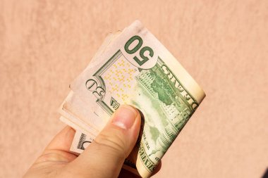 ABD Doları banknotlarıyla el ele tutuşan ve kağıt doku ve Amerikan Amerikan para biriminin sembollerini gösteren bir adam.