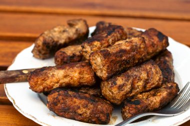 Ateşli ve dumanlı barbekü ızgarasında mici veya mititei adı verilen geleneksel Romen köftelerini hazırlamak