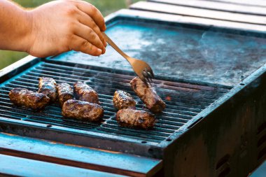Ateşli ve dumanlı barbekü ızgarasında mici veya mititei adı verilen geleneksel Romen köftelerini hazırlamak