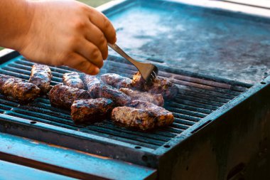 Ateşli ve dumanlı barbekü ızgarasında mici veya mititei adı verilen geleneksel Romen köftelerini hazırlamak