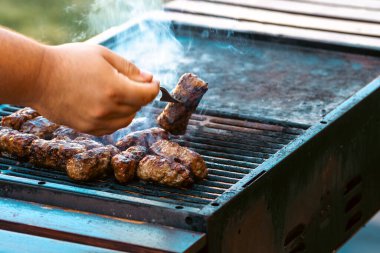 Ateşli ve dumanlı barbekü ızgarasında mici veya mititei adı verilen geleneksel Romen köftelerini hazırlamak
