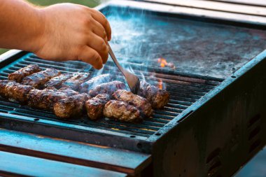 Ateşli ve dumanlı barbekü ızgarasında mici veya mititei adı verilen geleneksel Romen köftelerini hazırlamak