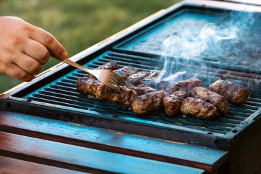 Ateşli ve dumanlı barbekü ızgarasında mici veya mititei adı verilen geleneksel Romen köftelerini hazırlamak