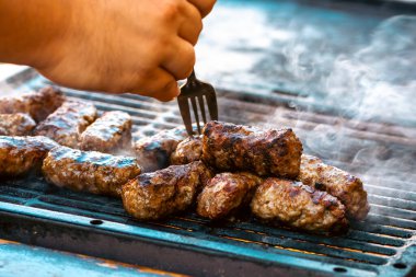 Ateşli ve dumanlı barbekü ızgarasında mici veya mititei adı verilen geleneksel Romen köftelerini hazırlamak