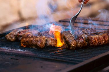 Ateşli ve dumanlı barbekü ızgarasında mici veya mititei adı verilen geleneksel Romen köftelerini hazırlamak