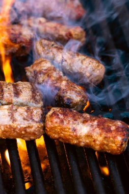 Ateşli ve dumanlı barbekü ızgarasında mici veya mititei adı verilen geleneksel Romen köftelerini hazırlamak