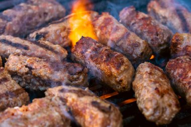 Ateşli ve dumanlı barbekü ızgarasında mici veya mititei adı verilen geleneksel Romen köftelerini hazırlamak