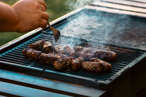 Ateşli ve dumanlı barbekü ızgarasında mici veya mititei adı verilen geleneksel Romen köftelerini hazırlamak