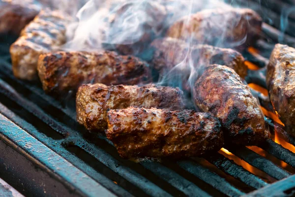 Ateşli ve dumanlı barbekü ızgarasında mici veya mititei adı verilen geleneksel Romen köftelerini hazırlamak