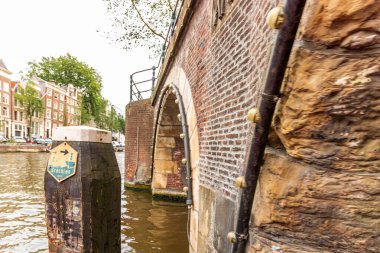 Amsterdam Hollanda 'da geleneksel tarihi binalarla Amstel nehrinin manzarası